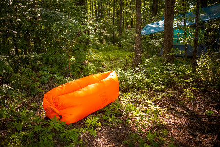 Orange inflatable sleeping pad in a forest setting