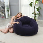 Load image into Gallery viewer, Woman lying on a navy inflatable bean bag chair in a room with plants and a mirror.
