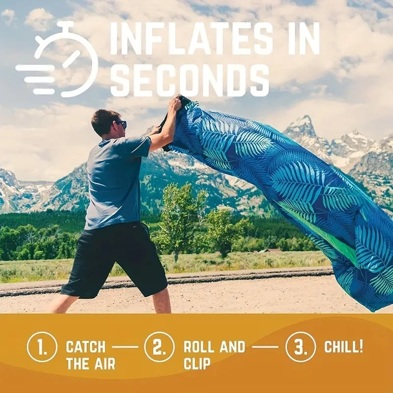 Person inflating a blue inflatable mat with mountains and trees in the background