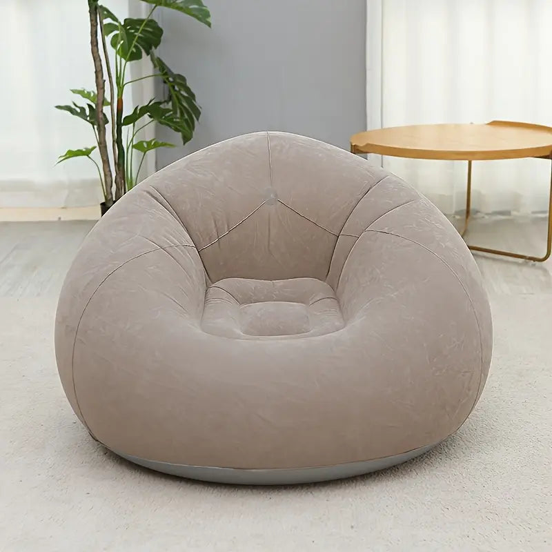 Beige inflatable chair in a room with a plant and table.